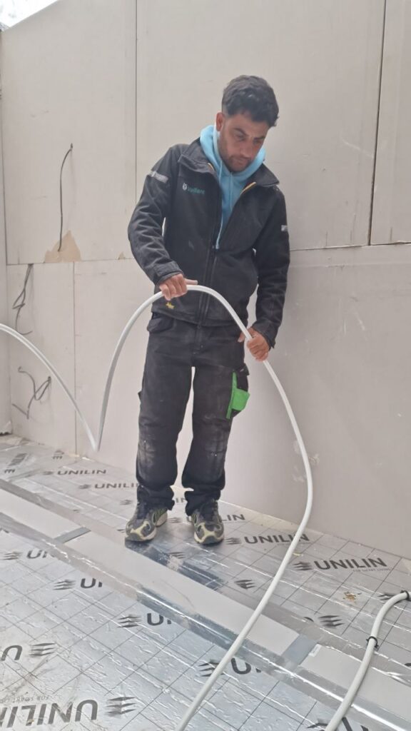 Engineer installing underfloor heating pipe loops in London home